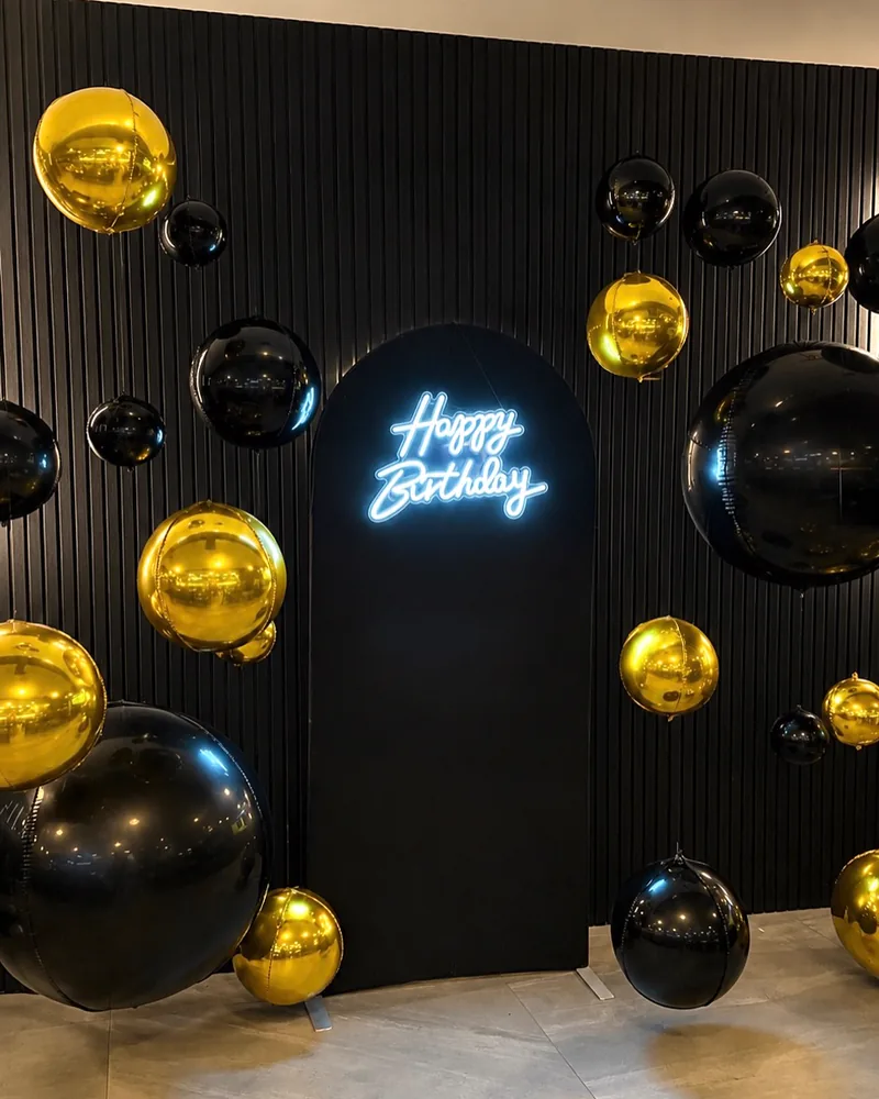 A Happy Birthday neon sign on a black arched backdrop