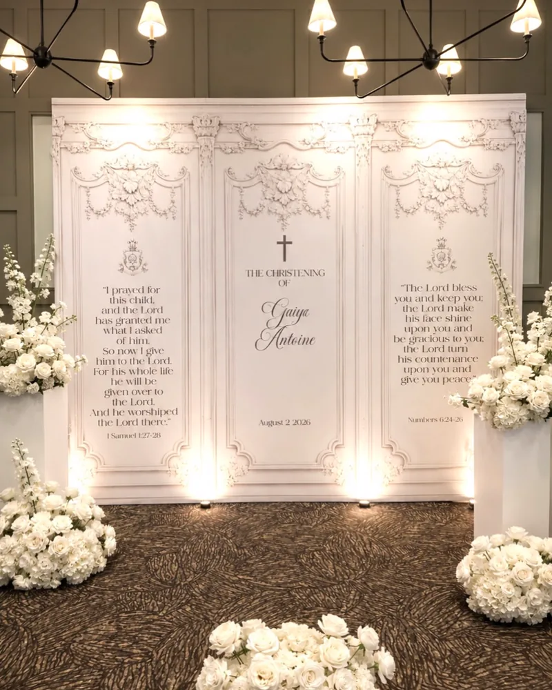 Printed backdrop panels with white flower arrangements at a christening