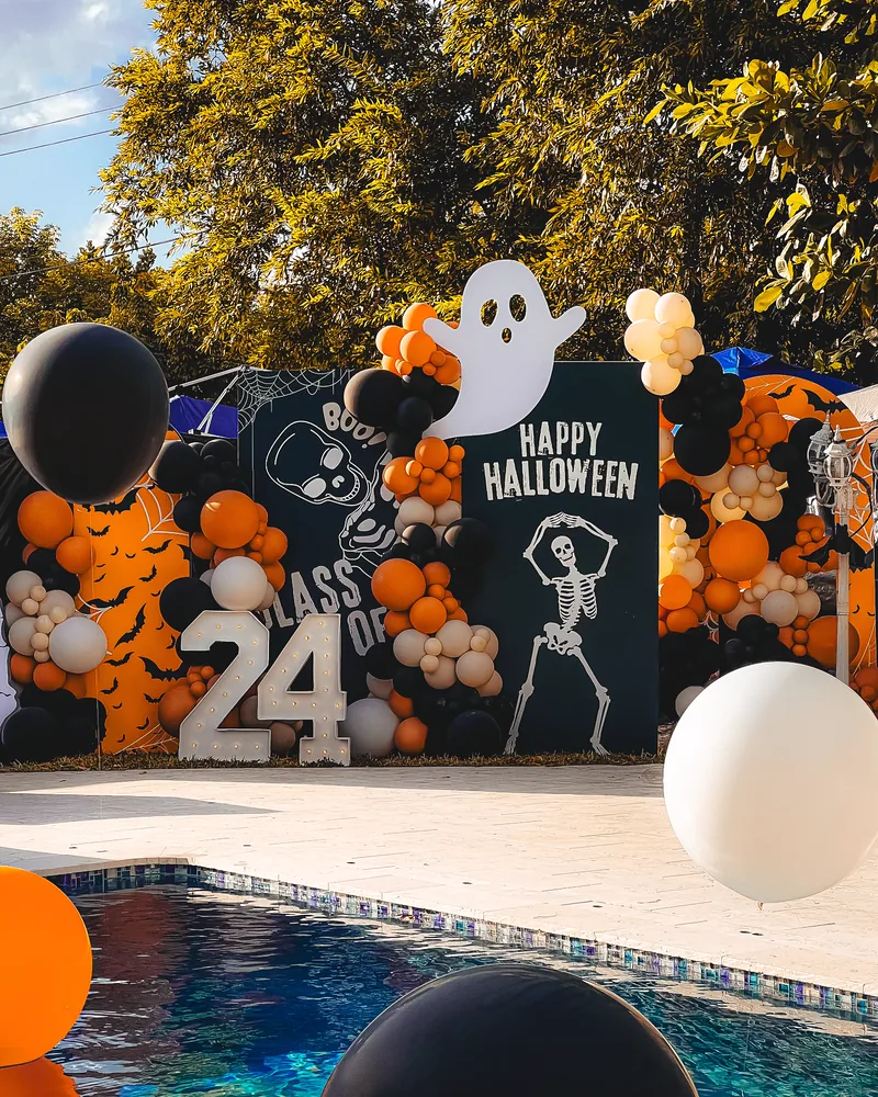 Light-up marquee numbers at a Halloween graduation party by a pool