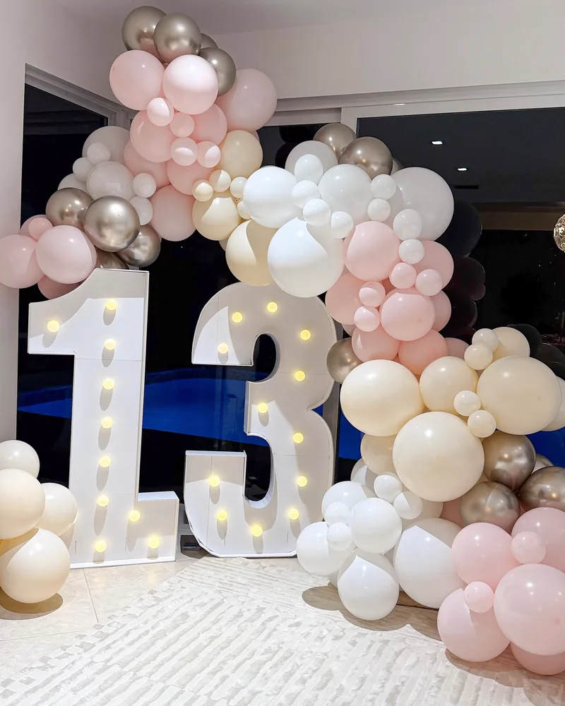 A light-up marquee number 13 beside a nude and chrome balloon garland