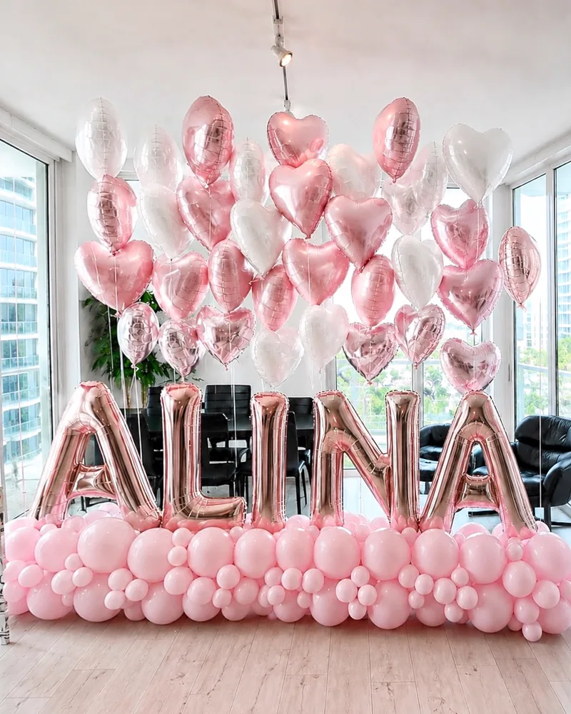 Giant rose gold foil name letters under a cloud of heart balloons