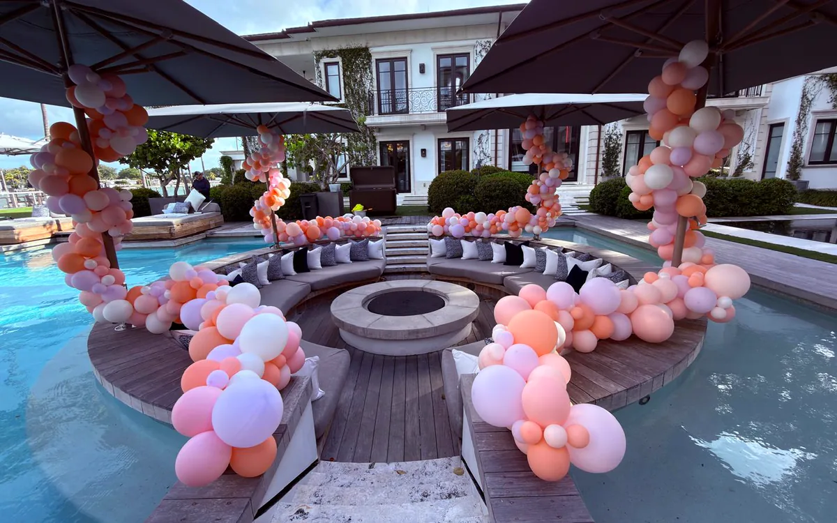 Balloon garlands wrapped around umbrellas at a poolside lounge