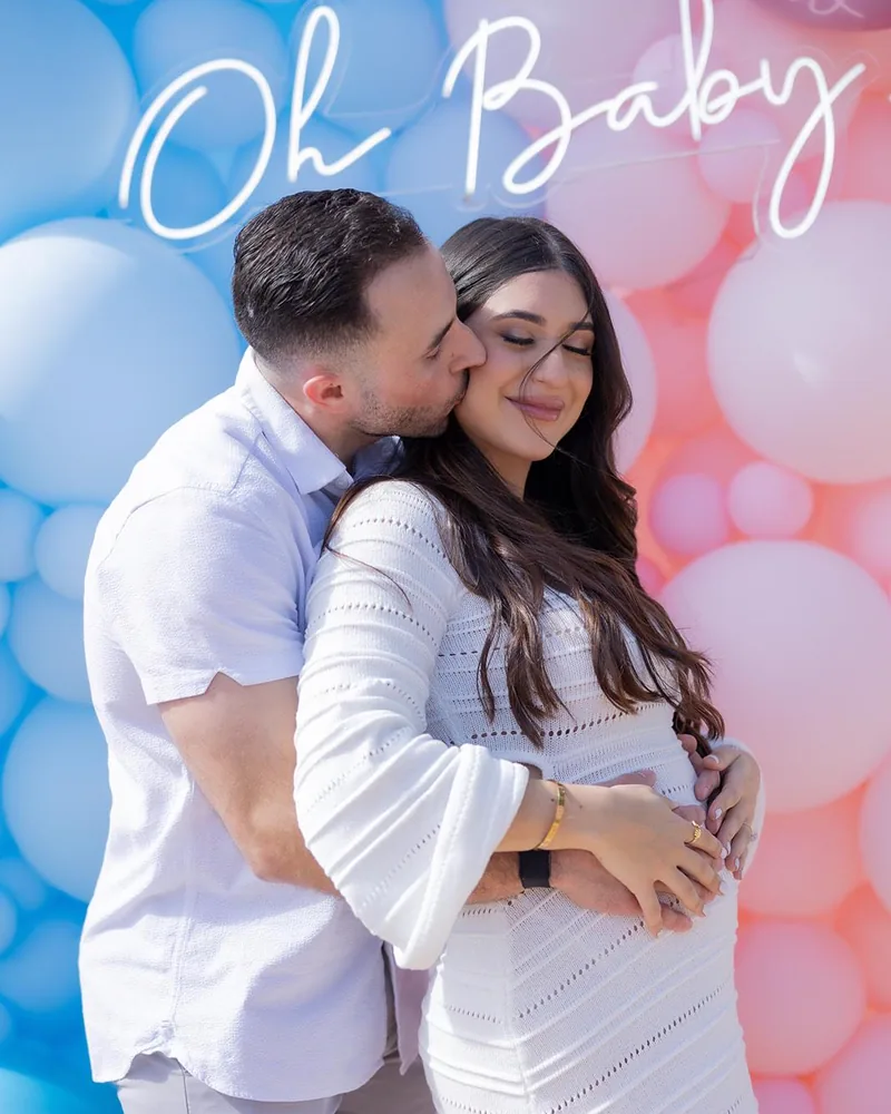 Expecting parents photographed in front of the Oh Baby balloon wall